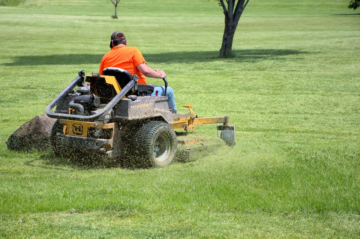Park maintenance worker mowing the lawn on a commercial riding mower
