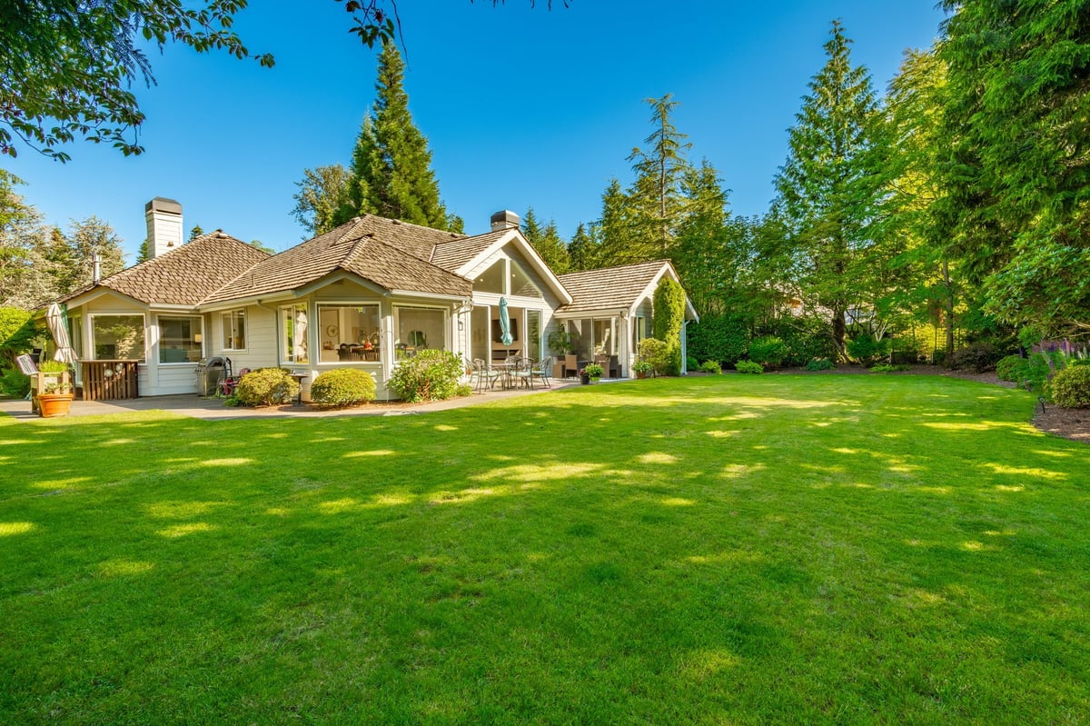 Beautiful residential home with lush landscaping, manicured lawn, and mature trees